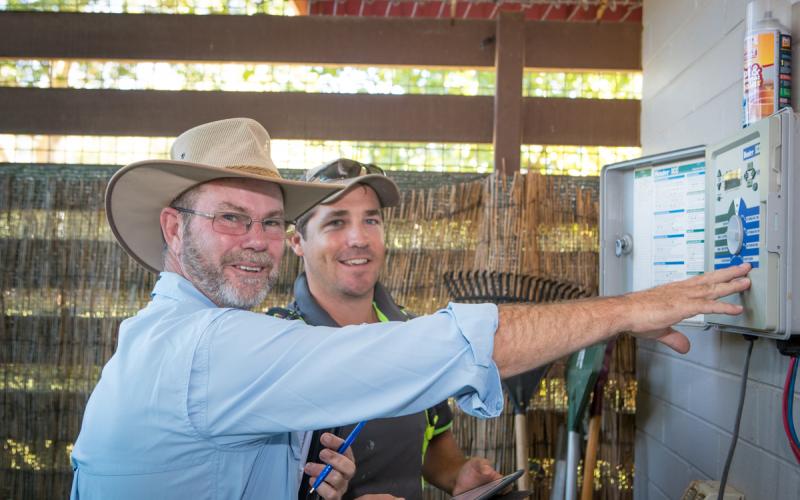 Smart irrigation controller with two men checking its set up